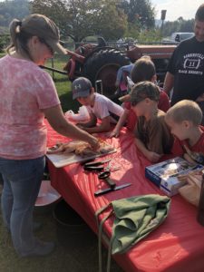 youth watching as volunteer processes poultry