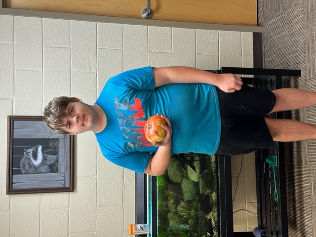 Youth participant holding his big tomato for the contest
