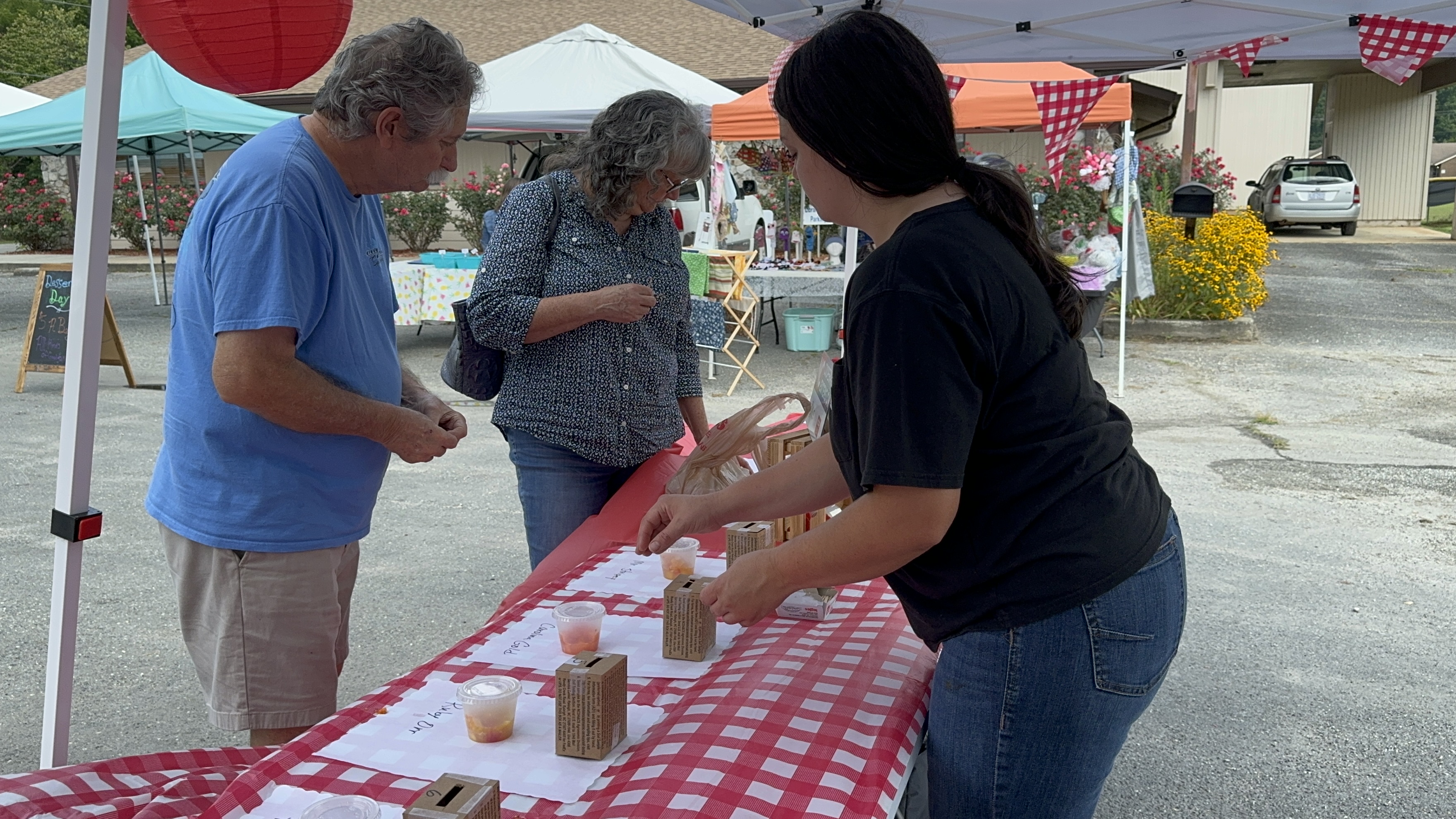 booth at local farmers market. two participants taste tomatoes