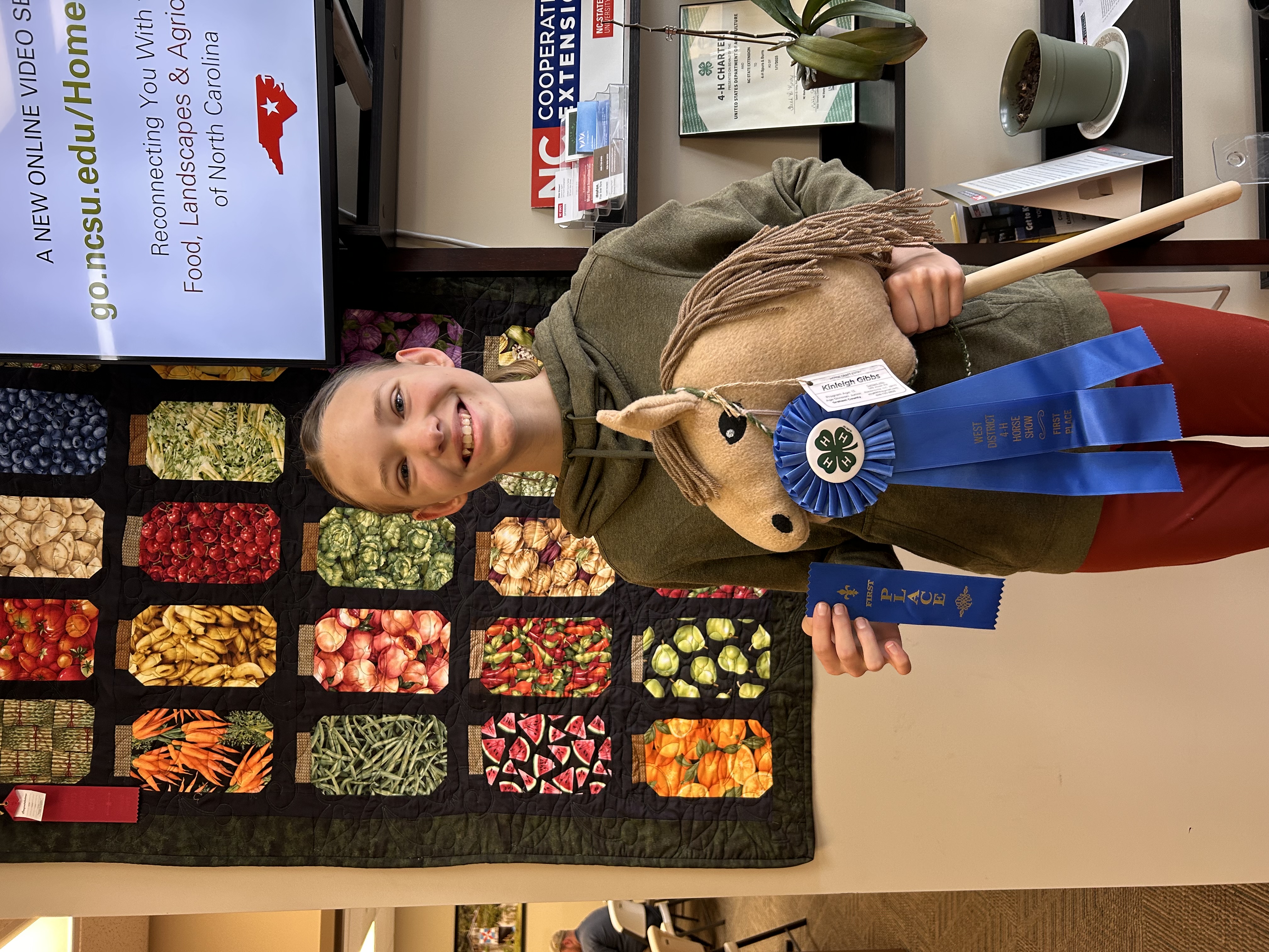 Photo of girl girl holding 2 blue ribbons and stick horse craft